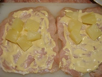 Отбитый кусочек мяса намазан соусом и нафарширован кусочками ананасов